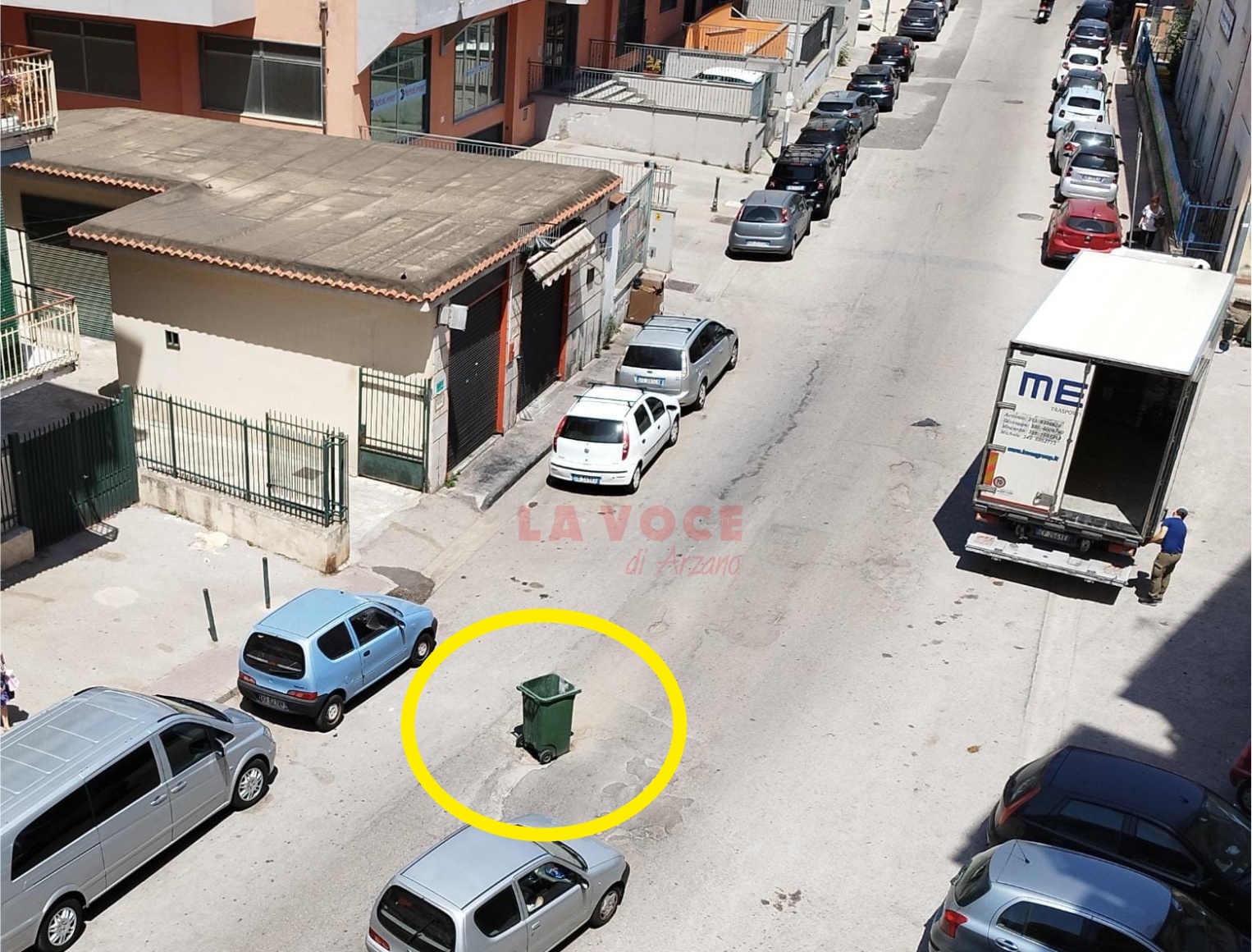 Via Ferrara, un cassonetto per segnalare una buca pericolosa